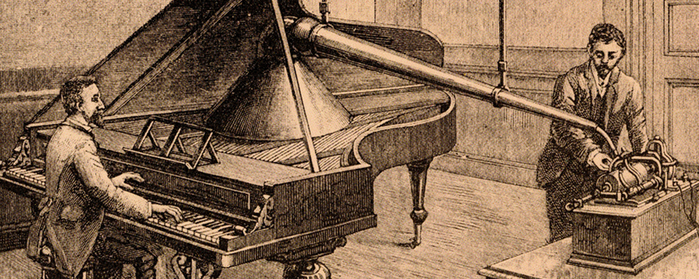 A vintage studio recording a piano onto an early phonograph